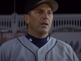 Billy Chapel in a baseball uniform with a dark sky in the background