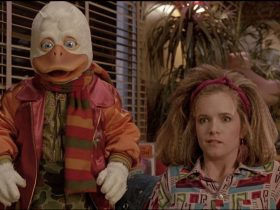 Howard the Duck and Lea Thompson as Beverly in a booth looking shocked in Howard the Duck