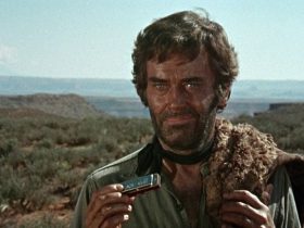 Frank from 'Once Upon a Time in the West,' holding a harmonica and smirking in an evil fashion