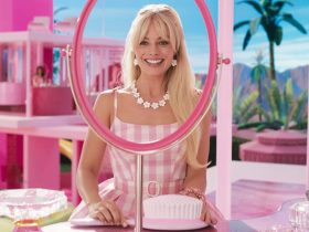 Margot Robbie looking at a vanity mirror in Barbie