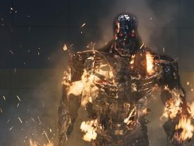 A Terminator robot covered in flames, recovering from a blast to the chest.