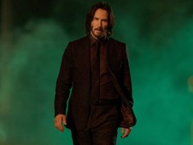 Keanu Reeves as John Wick walking through green mist in John Wick Chapter 4