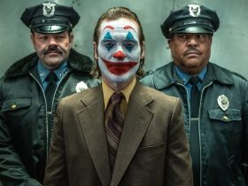 Arthur Fleck being escorted by police officers in Joker: Folie a Deux