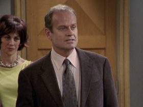 Frasier stands in his apartment with Ronee watching from behind