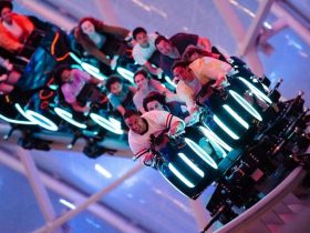 A promo shot of the TRON lightcycle ride, with excited passengers on board as it banks into a turn