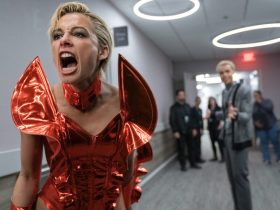 Clad in an ostentatious red dress, Skye Riley screams at someone off camera in a hallway in Smile 2